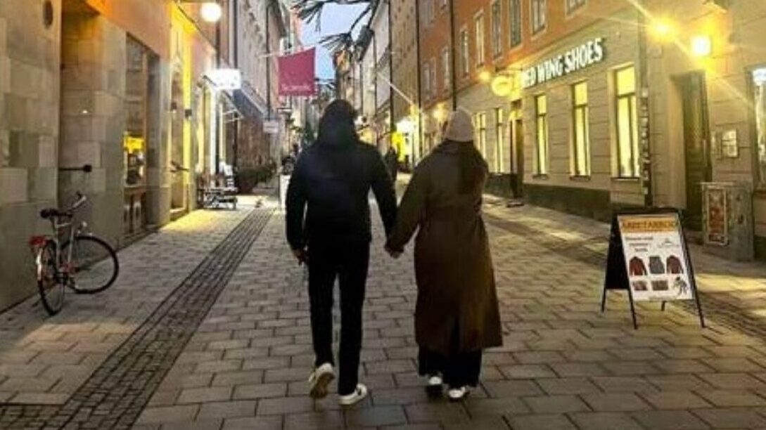 Ett par går och håller varandra i handen. Bild tagen bakifrån.